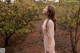 A woman in a pink dress standing in front of a bush.