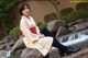 A woman sitting on a rock in front of a waterfall.