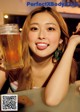 A woman sitting at a table with a glass of beer.