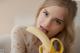 A woman holding a banana in front of her mouth.