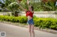 A woman in a red shirt and denim shorts playing basketball.