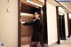 A woman in a black dress standing in an elevator.