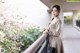 A woman standing on a balcony with a handbag.